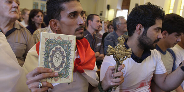 An Iraqi man carrying a cross and a Koran attends a mass at Mar Girgis Church in Baghdad